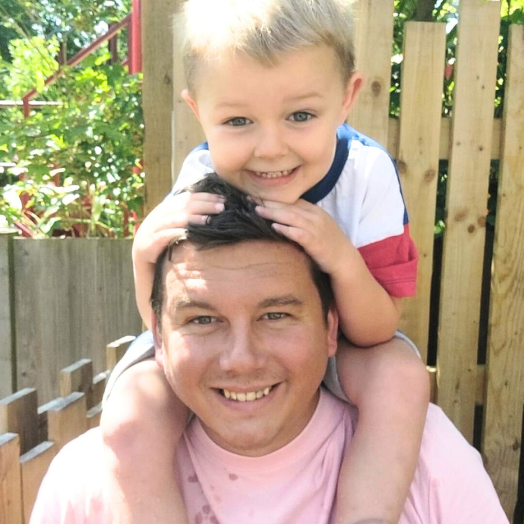 Man in pink t-shirt with child on his shoulders