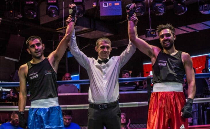 Boxing for charity, two boxers and one referee in line holding hands up