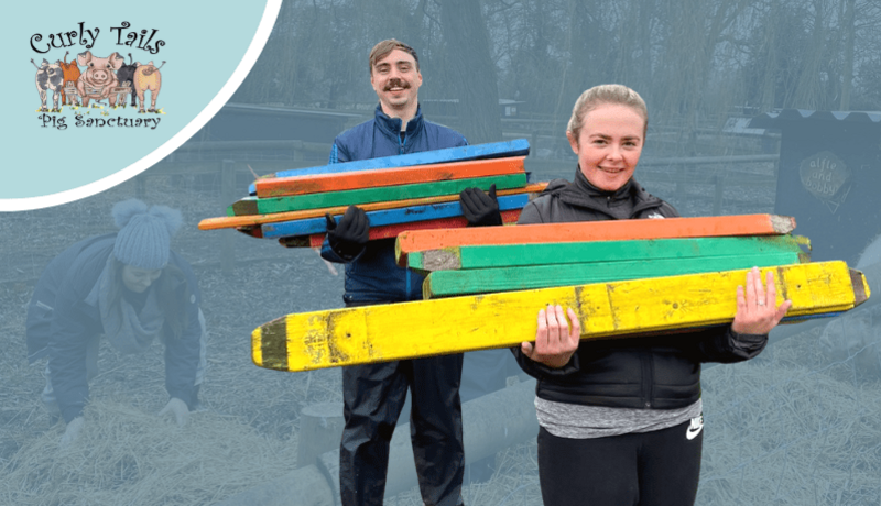 man and woman volunteering holding fence posts